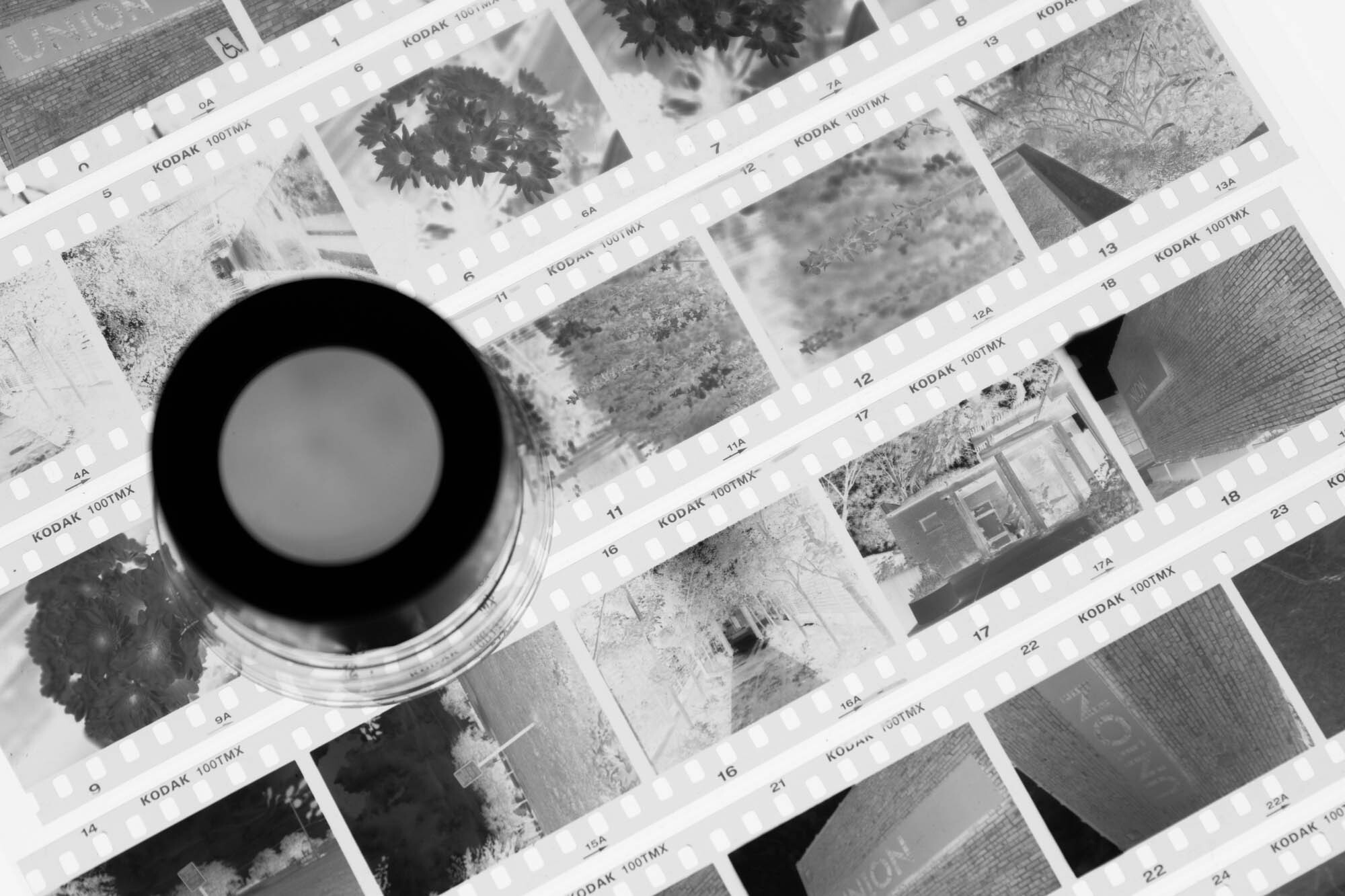 A Loupe Sits On A Page Of Black and White Film Negatives