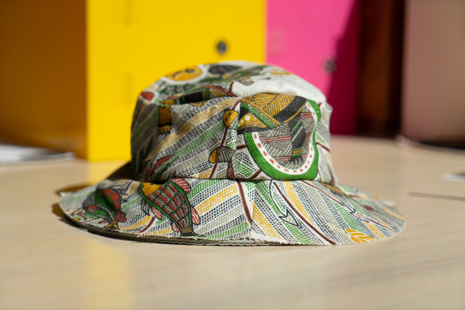 A colorful bucket hat sits on a light colored wood table