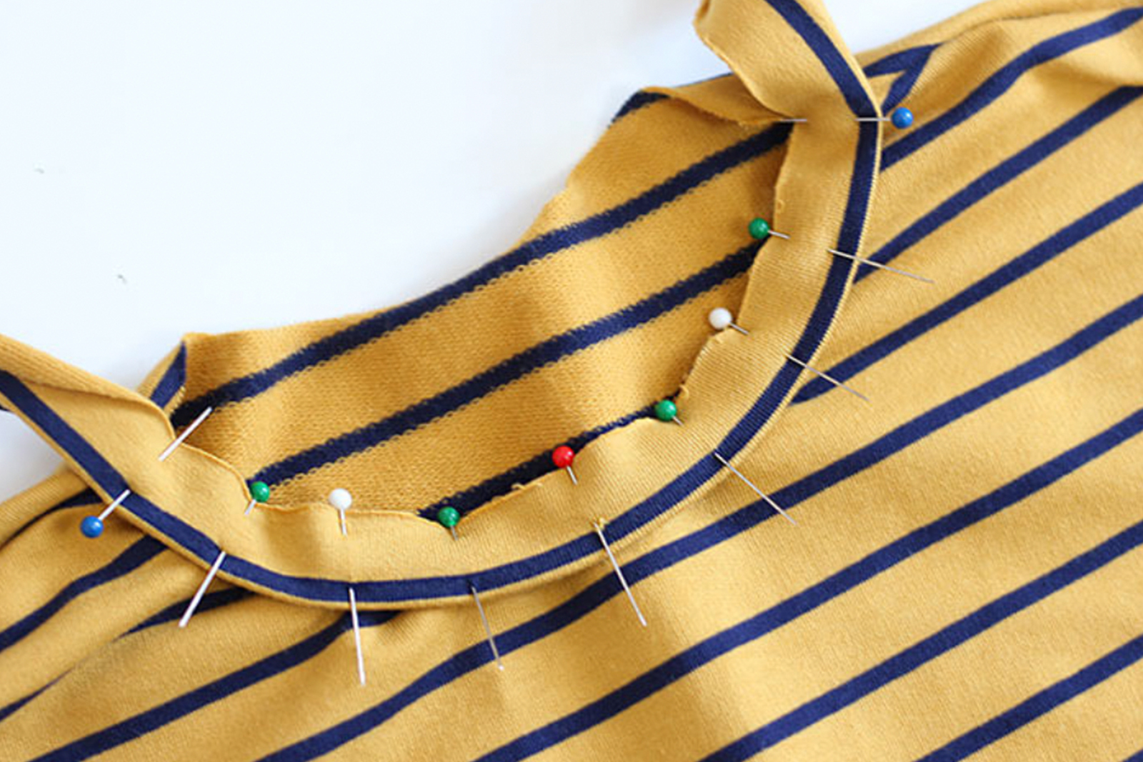 A sewn t shirt in progress with pins along the collar