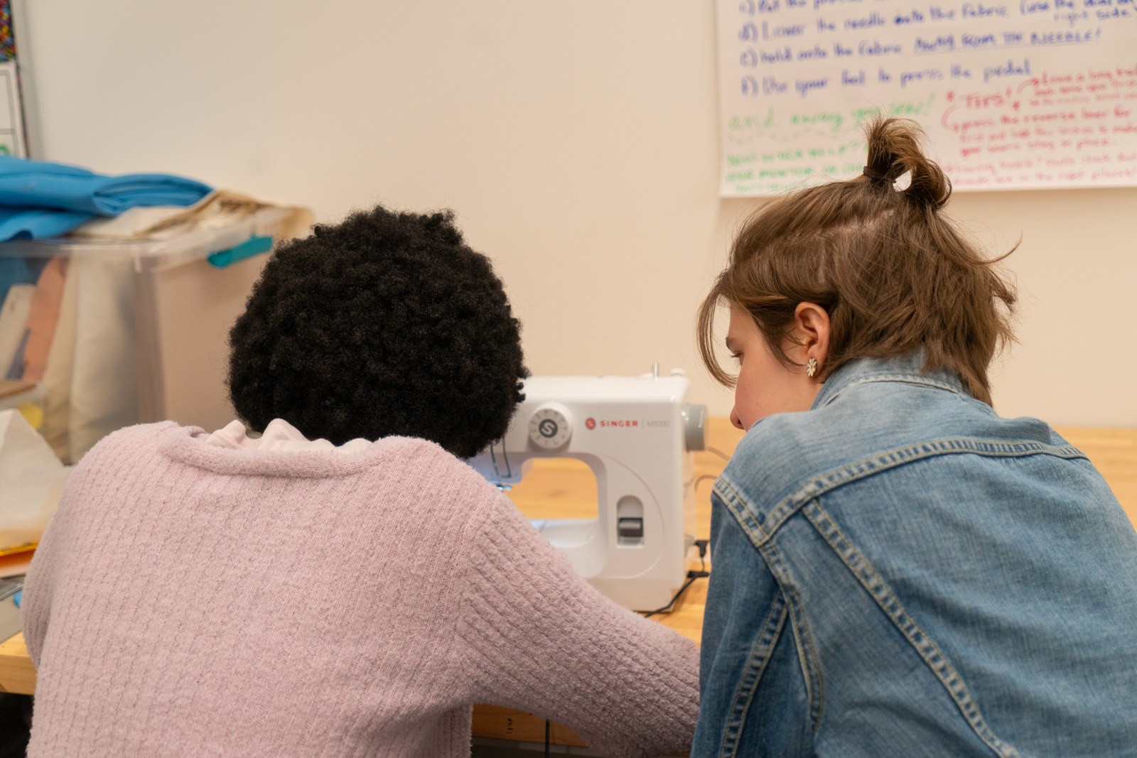 An MYA helps an Action Brigade artist with a sewing machine