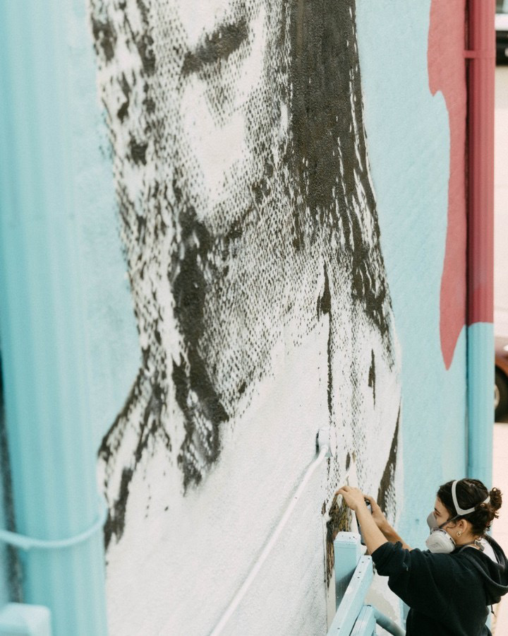 Artist Oria Simonini Spray Paints A Stencil On An Outdoor Wall Crop