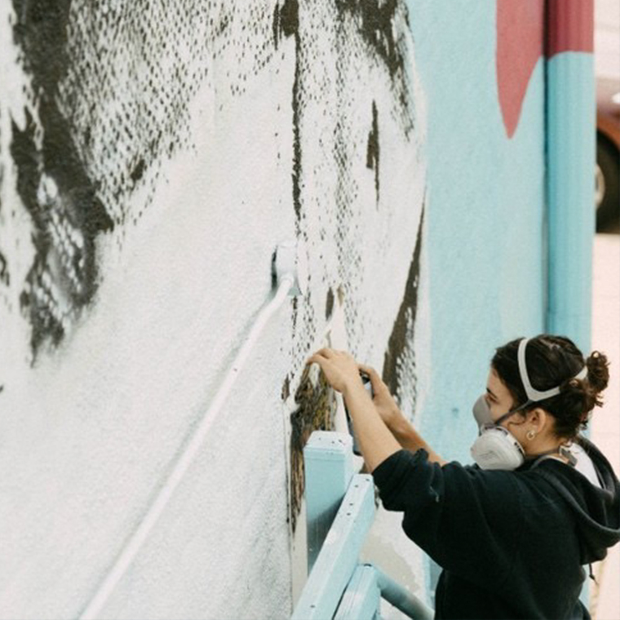 Artist Oria Simonini Spray Paints A Stencil On An Outdoor Wall