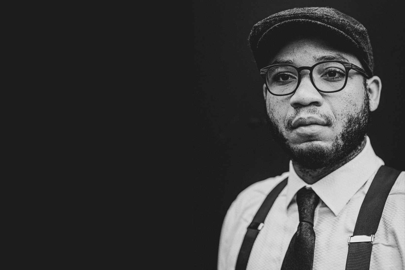 Black and white photo of a young Black man in glasses suspenders and a cap The words pursuing legacy are overlaid