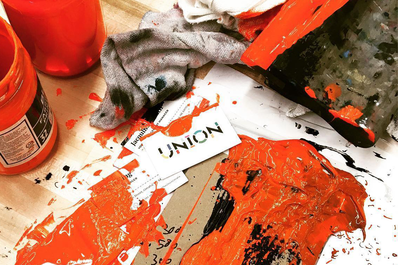 Co Op Distanced Membership Orange screen printing ink covers a messy work station that also inlcudes a blackened rag ink covered squeegie and Union business cards