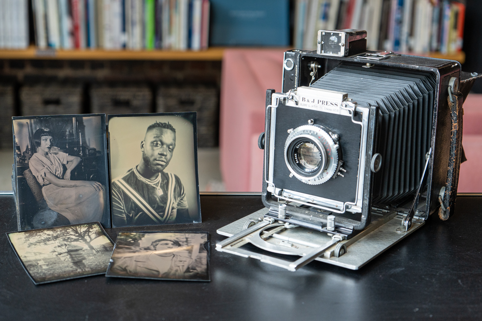 Dryplate Tintype portraits sit on a black table next to a large format camera with bellows