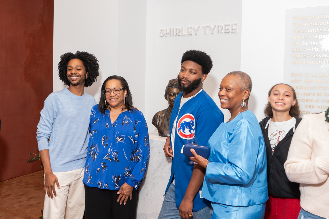 Family of Shirley Tyree pose next to a bronze bust of her in the lobby during the theater dedication event