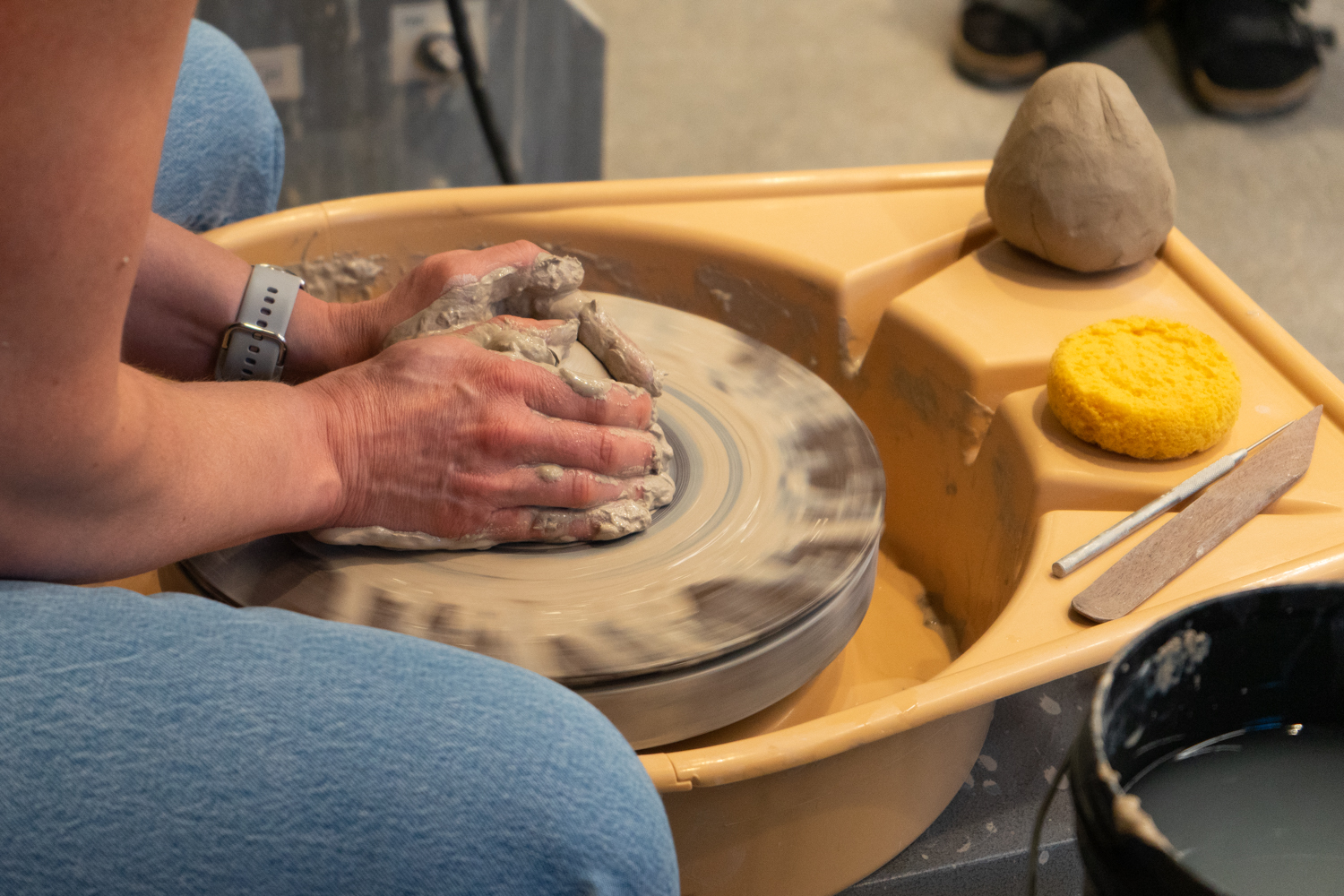 Hands form clay on a ceramics wheel