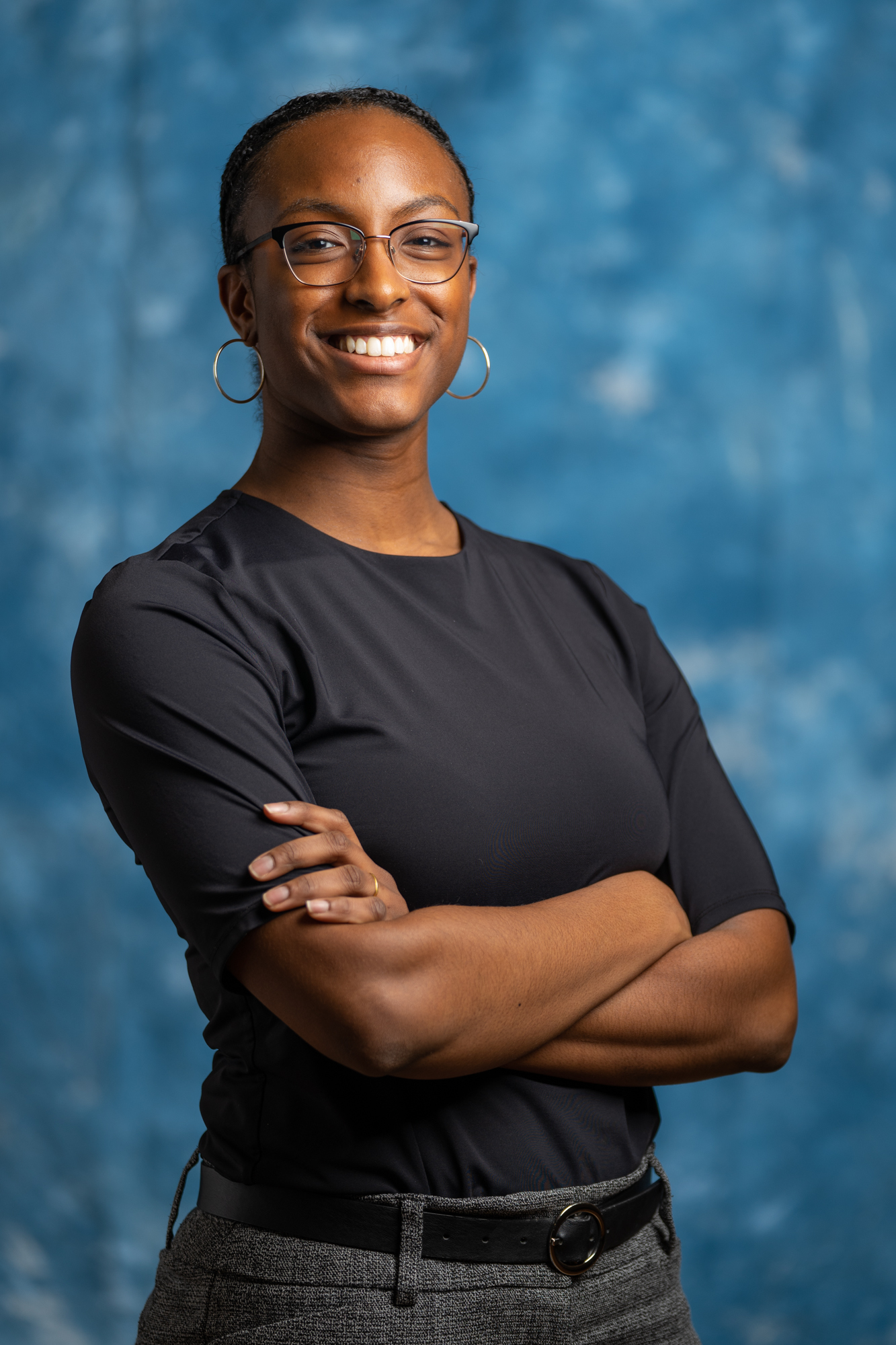 Populus Fund Grantee Jewel Rodgers smiles with arms folded against an abstract blue background