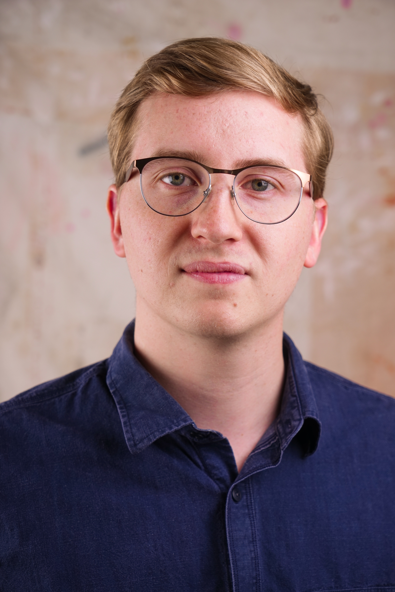 Populus Fund Grantee Nick Beaulieu looks at the camera in front of a bright abstract background