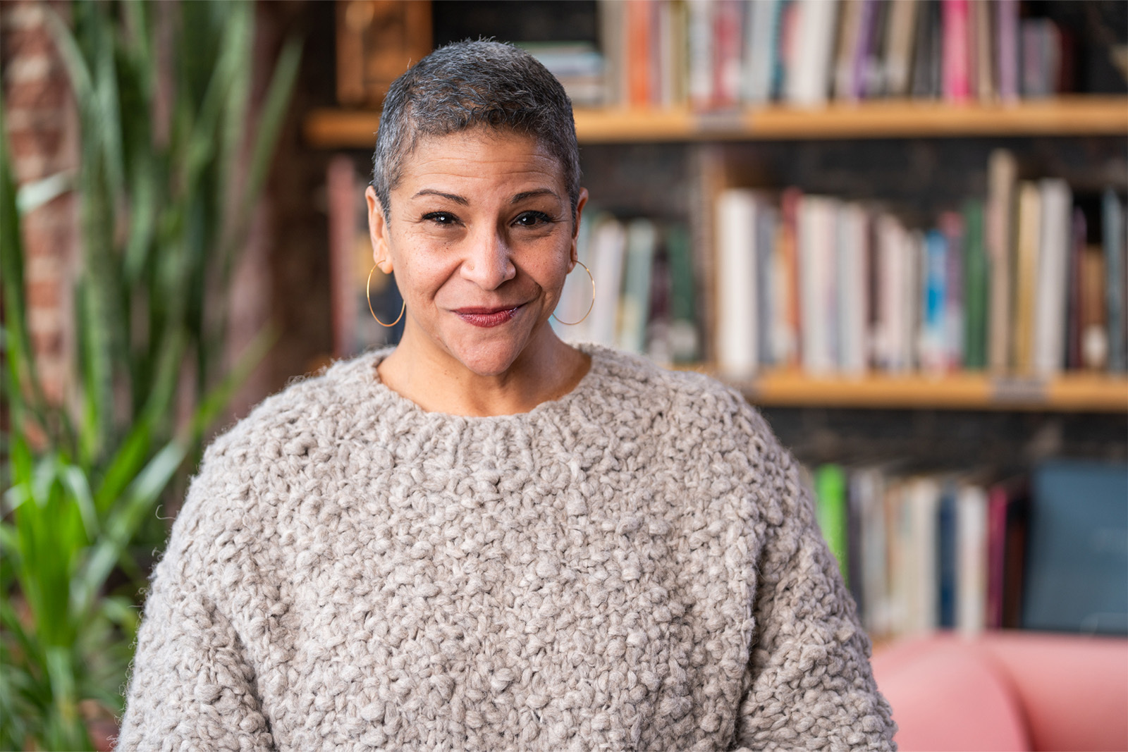 Portrait photo of Brigitte Mc Queen sitting in the lobby of The Union in front of a wall of books