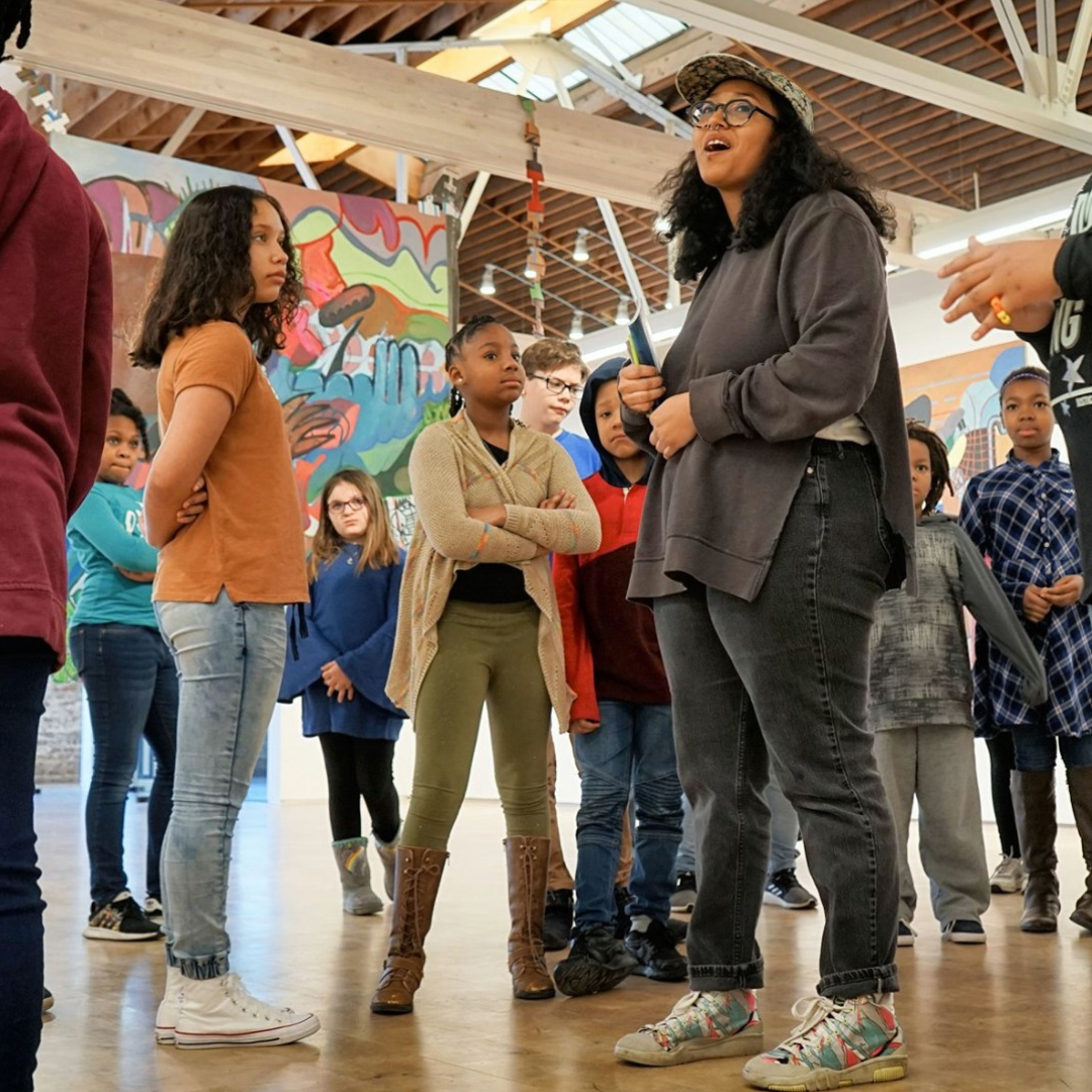 Several young people and artist Thalia Rodgers standing in the gallery during a field trip