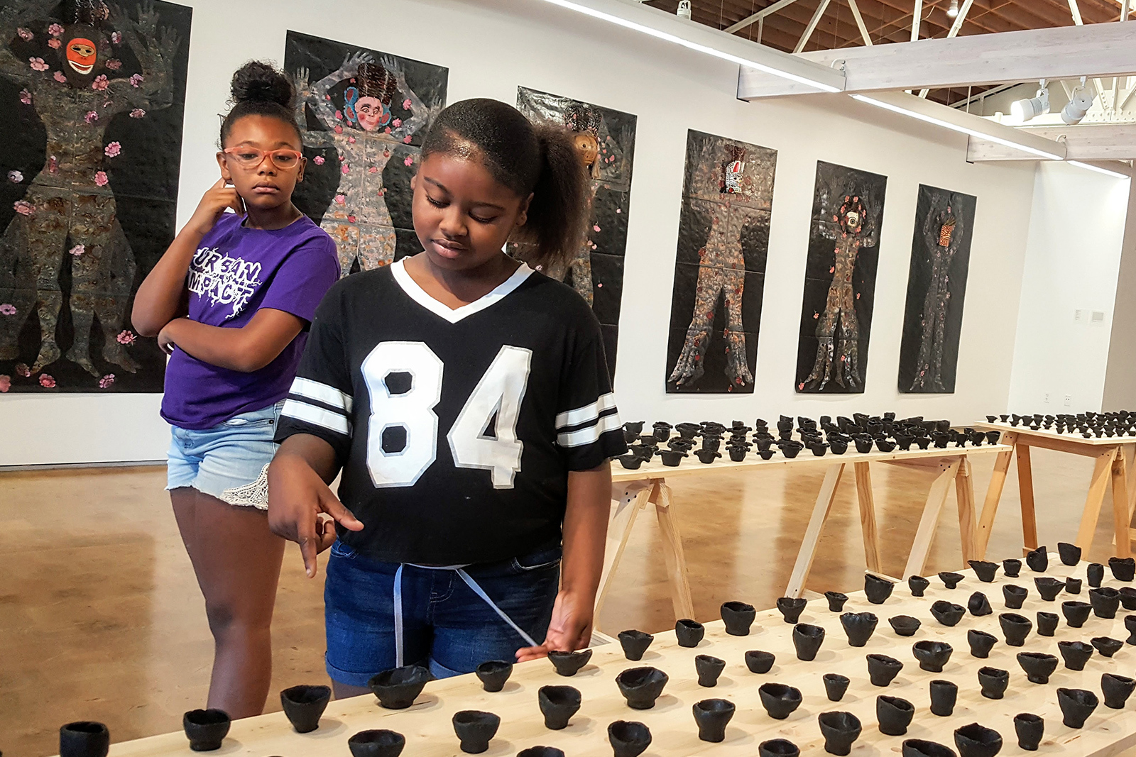 Two young girls examine small sculptures in the gallery
