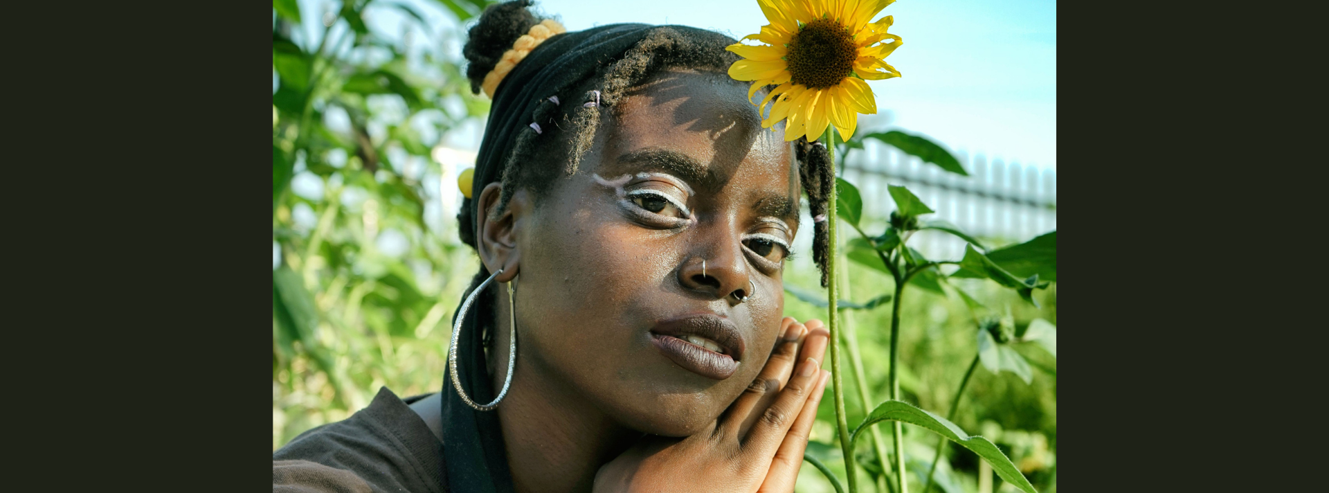 Banner Alajia Mc Kizia portriat in garden next to a sunflower