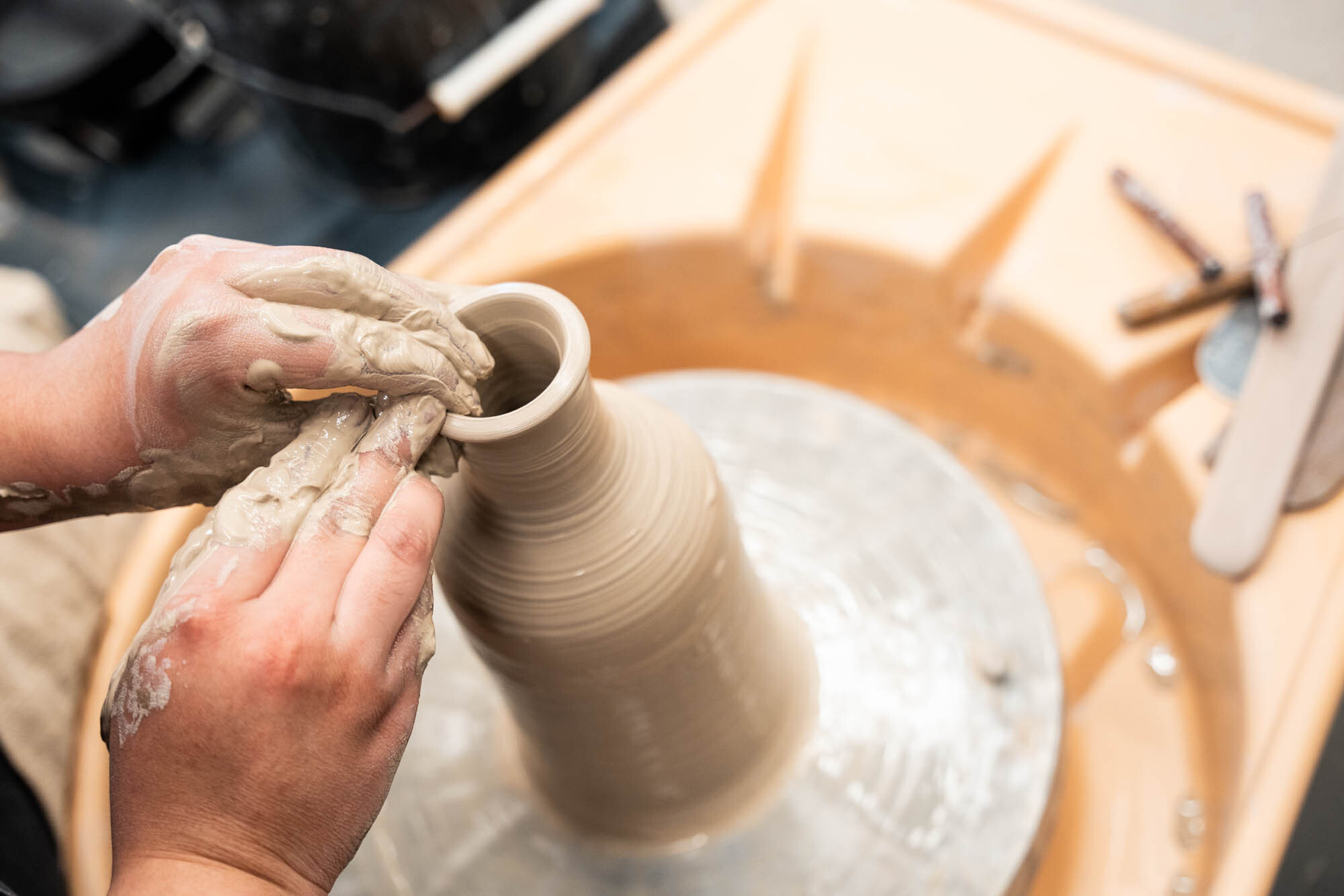 Hands pull a vase form on a wheel in the union ceramics studio