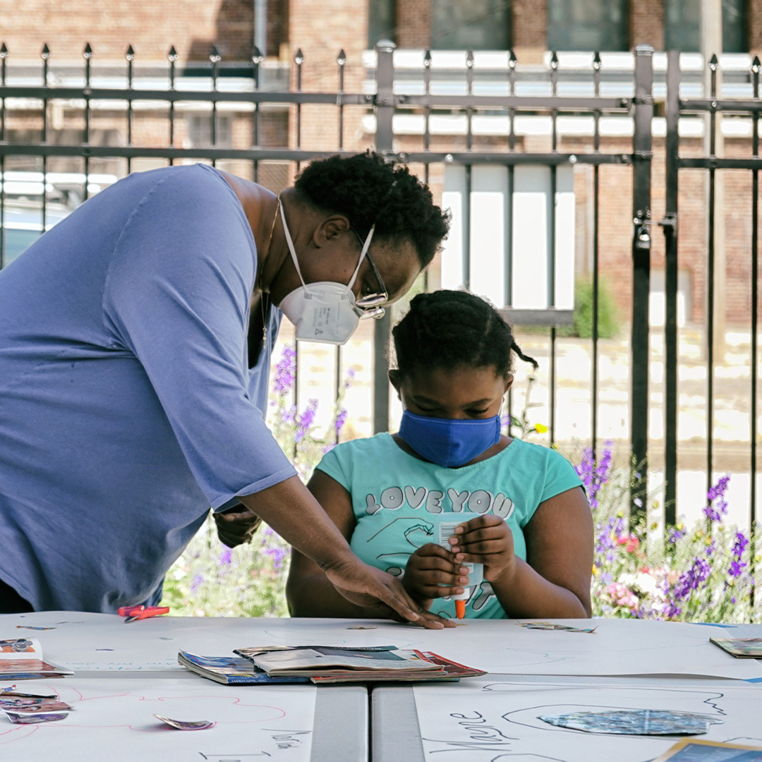 Outdoor art activity a young artists wearing a mask uses glue for a collage sitting outside