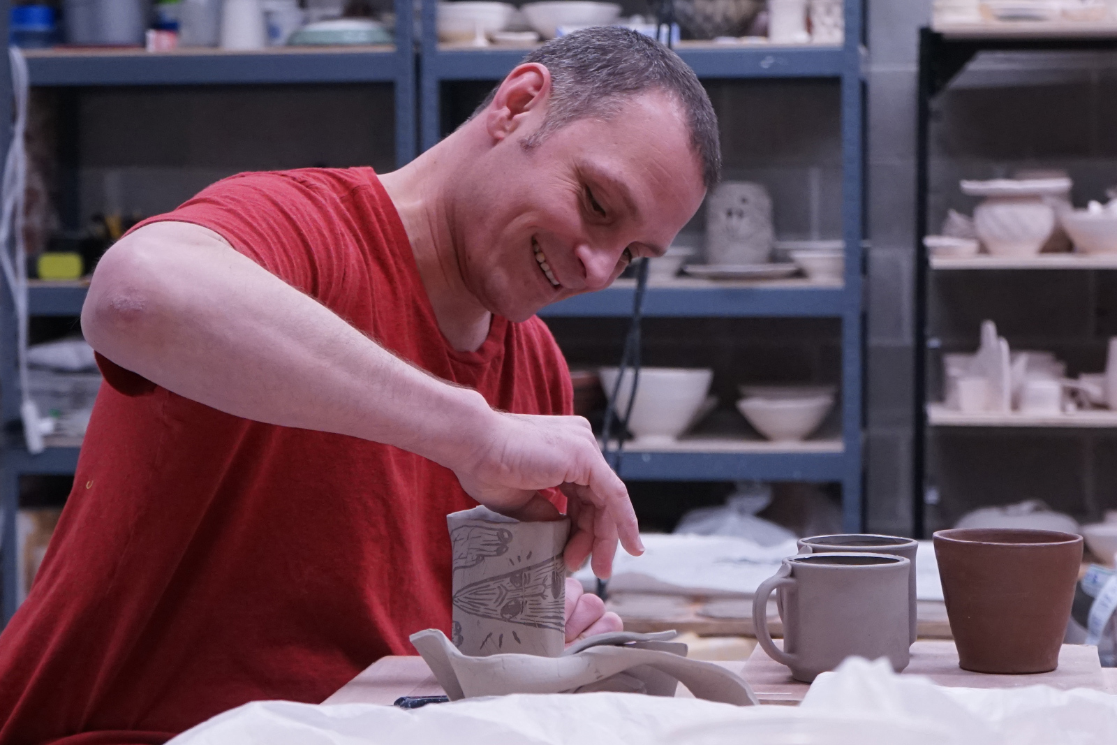 artist at work hand building a mug with a slab of clay in the ceramics studio