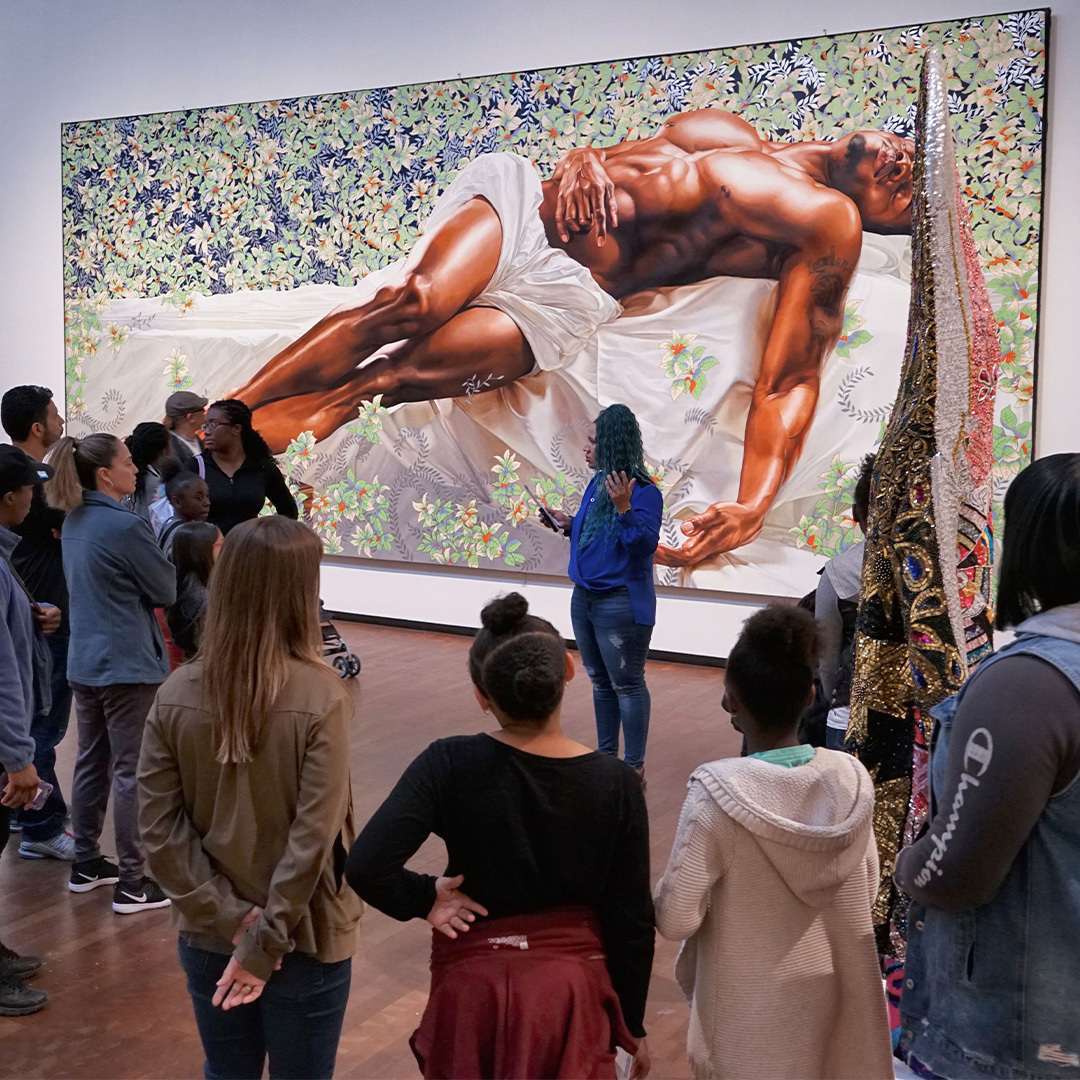 Youth field trip a group stands in a circle listening to an instructor speak in the center at Joslyn Art Museum